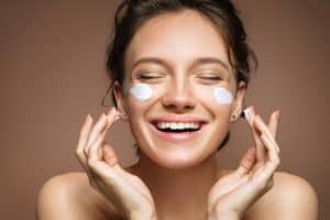 happy woman putting on face cream