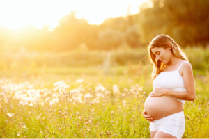 woman showing off her baby bump in the foreground in a field